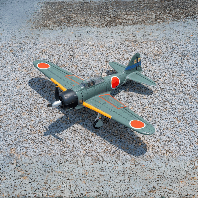 FMS Zero A6M3 V2 PNP airplane with distinctive Japanese design on gravel surface